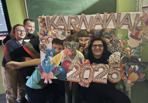 Uczniowie w maskach karnawałowych z Panią Dyrektor Anną Jagielską