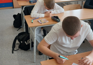 Uczniowie wypełniają pocztówki.
