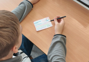 Uczniowie wypełniają pocztówki.
