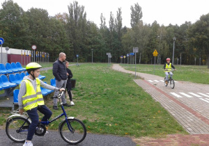 Jeden uczeń jedzie na rowerze, drugi oczekuje na swoją kolej.