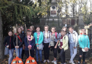 Zdjęcie uczennic – uczestników kwesty na tle jednego z nagrobków.