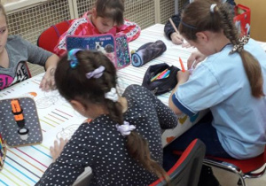 Uczniowie kolorują przygotowane rysunki dyni oraz wycinają nietoperze.