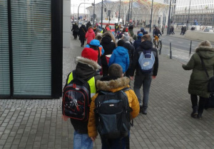 Dzieci idą parami po chodniku.
