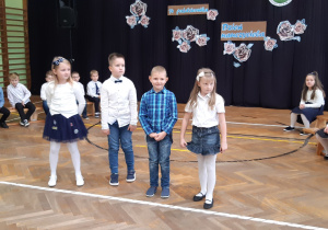 Grupa uczniów w galowych strojach recytuje wiersze.