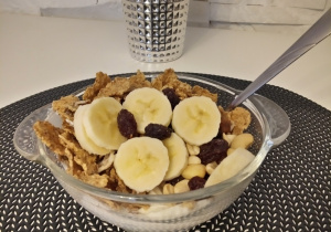 Miseczka jogurtu z plasterkami banana, suszonymi owocami, orzechami