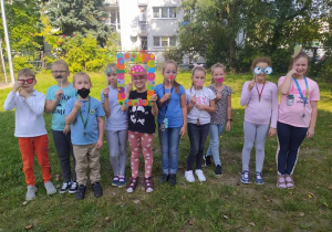 Grupa dzieci stojąca na tle drzew w kolorowych strojach
