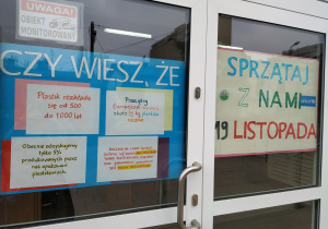 Kolorowe plakaty rozwieszone na drzwiach szkoły promujące akcję sprzątania osiedla