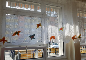 Papierowe motyle przypięte do firanek w świetlicy szkolnej.