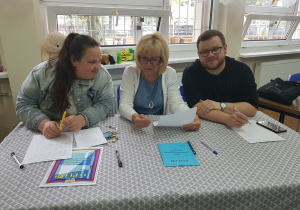 Jury konkursu - trzy osoby siedzą przy stole.