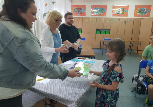 Dziewczynka odbiera nagrodę z rąk członka jury.