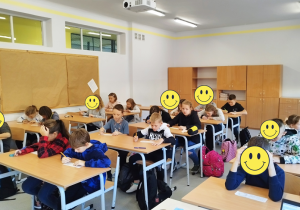 Uczniowie siedzący w ławkach i rozwiązujący zadanie z tabliczką szczęścia