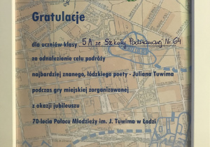W białej ramce za szkłem gratulacje dla uczniów za odnalezienie celu podróży Juliana Tuwima.