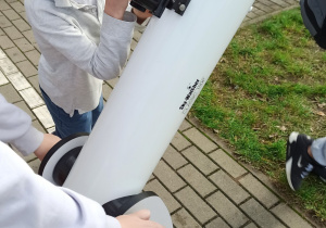 Uczniowie oglądają zaćmienie przez szkolny teleskop.