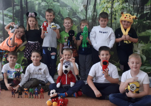 Grupa dzieci przebranych za bajkowe postacie z pluszakami oraz zabawkami w ręku