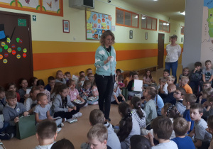 Uczniowie siedzą i słuchają nauczyciela, którzy wyczytuje wyróżnionych