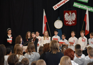 Grupka uczniów podczas programu artystycznego, dziewczynka gra na skrzypcach