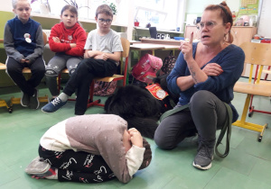 Opiekunka psa instruuje grupę uczniów, jak bezpiecznie zachowywać się wobec psa.