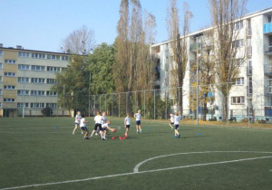 Uczniowie grają w piłkę na boisku do piłki nożnej