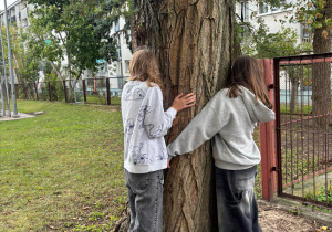 Uczniowie przytulają się do drzewa.