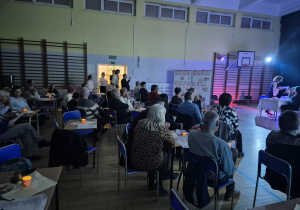 Dziadkowie na widowni siedzący przy stolikach