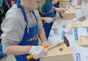 Uczennice za pomocą młotków wbijają gwoździe i łączą elementy budki dla ptaków.