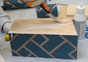 Uczeń rozprowadza pędzlem klej do tapet.