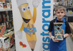 Uczeń prezentuje wykończoną budkę dla sikorek.