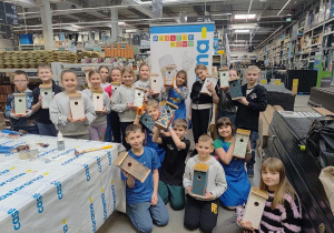 Cały zespół klasowy prezentuje wykonane budki dla ptaków.