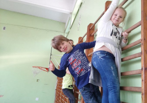 Czworo dzieci wspina się po drabinkach w sali gimnastycznej.