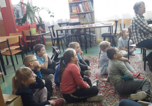 Grupa uczniów ogląda w bibliotece film tematyczny „Zimowe krajobrazy”.