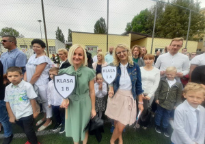 Pani Iza i pani Agnieszka z tabliczkami w rękach oczekują na boisku na pierwszoklasistów.