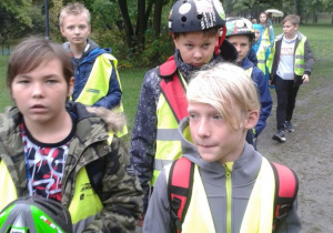 Kilku chłopców ubranych w kamizelki odblaskowe oraz kaski rowerowe w drodze na Motodrom.