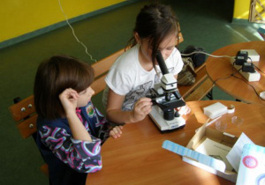 Dwie uczennice z klasy 4 a mikroskopują.