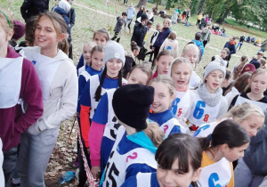 Grupa dziewcząt w strojach sportowych i kamizelkach z numerami zawodnika.