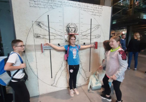 Dziewczynka mierzy rozpiętość swoich ramion na specjalnej macie interaktywnej w Centrum Nauki Kopernik.