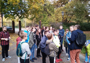Grupa uczniów wraz z nauczycielem i przewodnikiem w Parku Źródliska