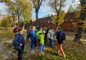 Grupa uczniów wraz z nauczycielem i przewodnikiem w Parku Źródliska