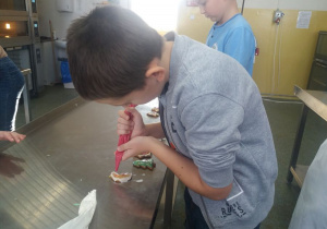 Uczeń ozdabia lukrem pierniki.