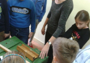 Nauczyciel pokazuje uczniom stanowisko do obróbki drewna.