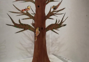 Wycinanka z papieru przedstawia drzewo i ptaki na gałęziach.