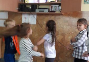 Uczniowie tańczą oraz śpiewają do projekcji filmu w takt piosenki "Hulajnoga".