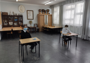 Uczniowie siedzą w ławkach w sali egzaminacyjnej