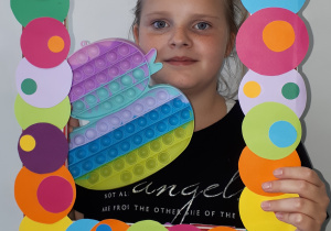 Dziewczynka trzymająca kolorową ramkę i pop it