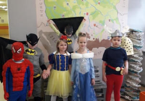 Grupa dzieci przebrana za Superbohaterów tj. Batman, Spiderman oraz Księżniczki pozują do zdjęcia na tle mapy Polski.