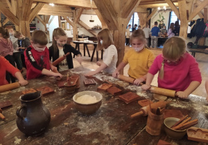 Dzieci wałkują ciasto przy użyciu drewnianych wałków
