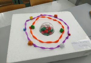 Model atomu fluoru, którego protony, neutrony i elektrony wykonane z materiałowych kuleczek zostały umieszczone na styropianie
