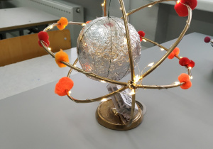 Model atomu sodu, wykonany z folii aluminiowej, kolorowych materiałowych kuleczek i lampek choinkowych