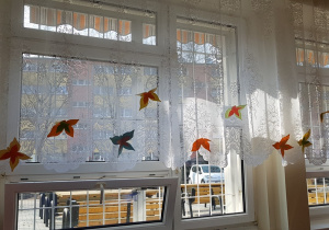 Papierowe motyle przypięte do firanek w świetlicy szkolnej.
