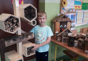 Uczeń prezentuje domek wykonany z drewnianych deseczek, kilkupiętrowy.