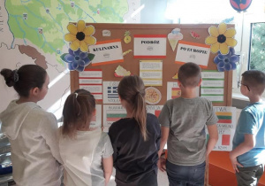 Uczniowie zapoznają się z informacjami zgromadzonymi na tablicy "Kulinarna podróż po Europie"